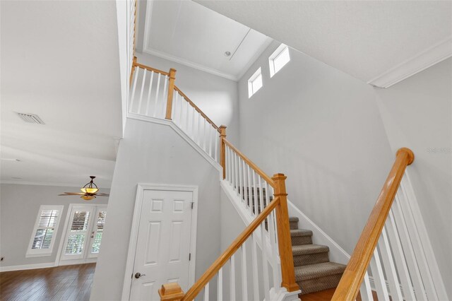 stairs with a high ceiling, ornamental molding, and a healthy amount of sunlight