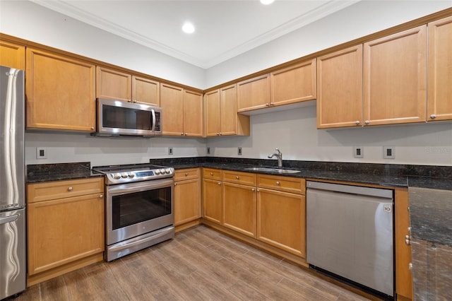 kitchen with wood-type flooring, appliances with stainless steel finishes, crown molding, dark stone counters, and sink