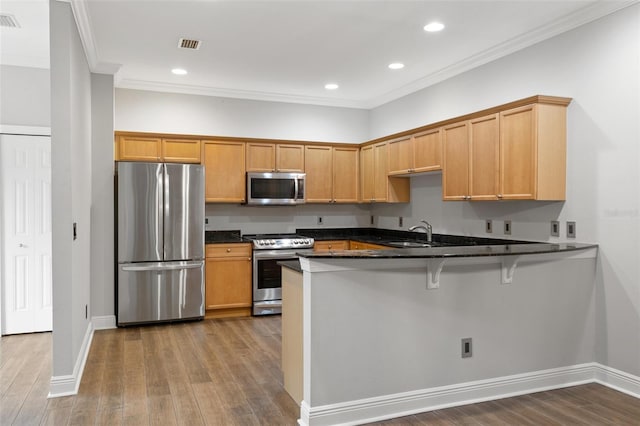 kitchen with sink, kitchen peninsula, dark stone counters, crown molding, and appliances with stainless steel finishes