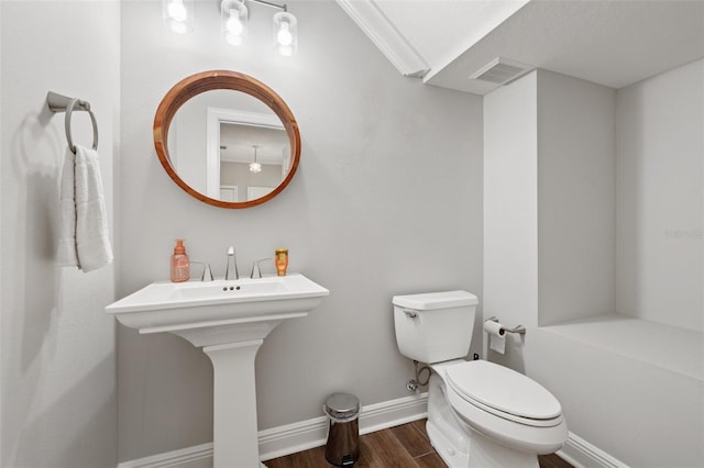 bathroom featuring hardwood / wood-style floors, crown molding, and toilet