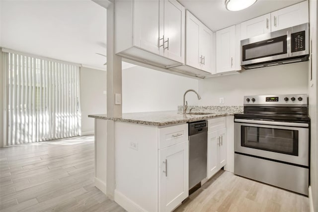 kitchen featuring white cabinetry, sink, light stone countertops, and appliances with stainless steel finishes