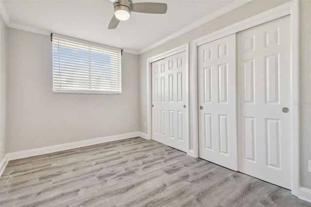 unfurnished bedroom with ceiling fan, crown molding, light hardwood / wood-style floors, and two closets