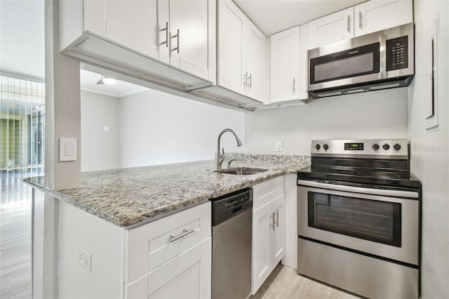 kitchen with light stone countertops, stainless steel appliances, white cabinetry, and sink