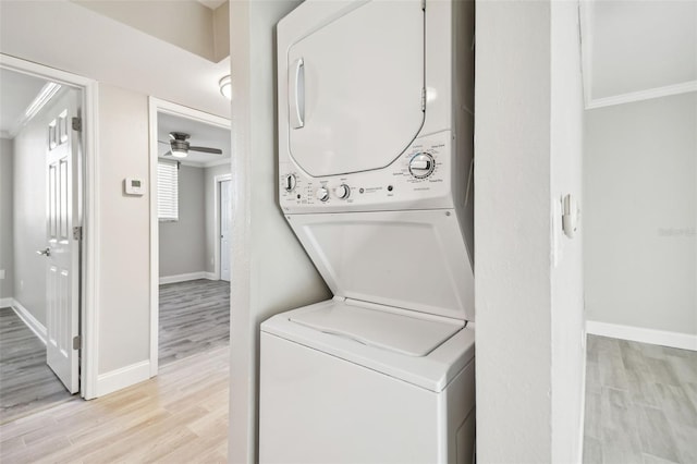 laundry room with light wood-type flooring, stacked washing maching and dryer, ceiling fan, and crown molding