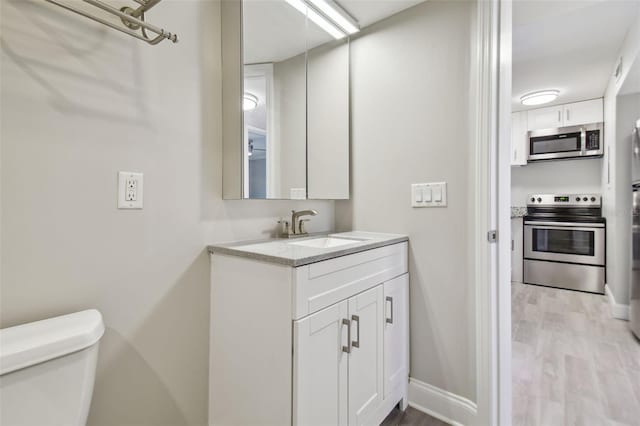 bathroom with hardwood / wood-style floors, vanity, and toilet