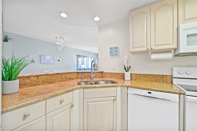 kitchen featuring light stone counters, sink, and white appliances