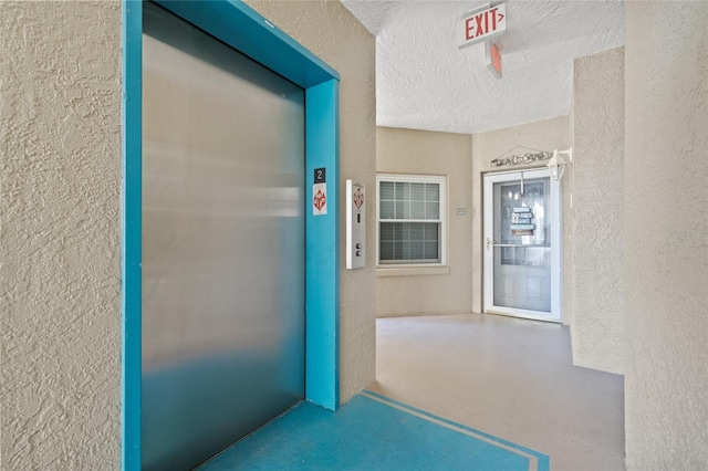 hallway featuring elevator and a textured ceiling