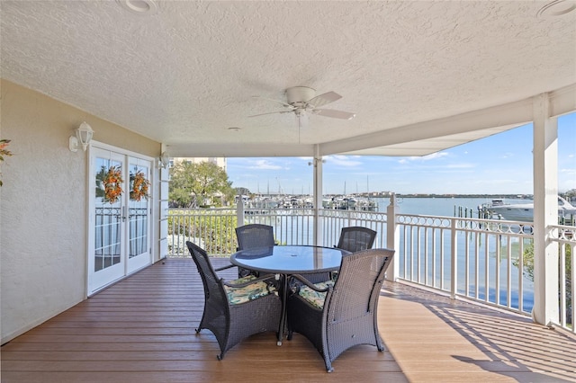 wooden deck with ceiling fan and a water view