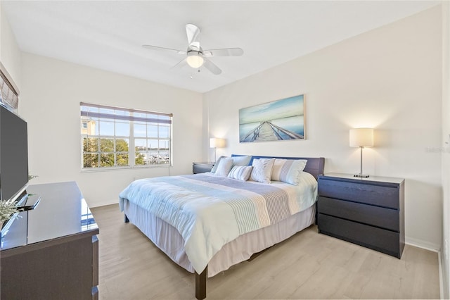 bedroom featuring light wood finished floors, a ceiling fan, and baseboards