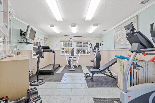 workout room with a textured ceiling, ornamental molding, wainscoting, and visible vents