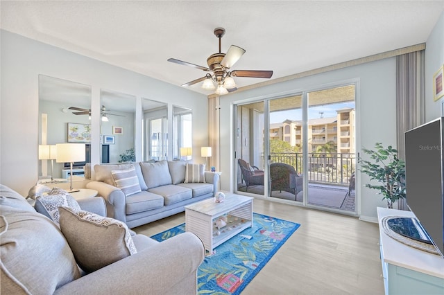 living area featuring ceiling fan, light wood-type flooring, and baseboards