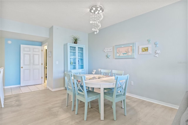 dining room with baseboards, a notable chandelier, and wood finished floors