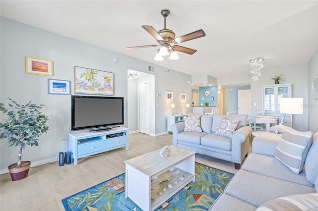 living room featuring baseboards, a ceiling fan, visible vents, and light wood-style floors