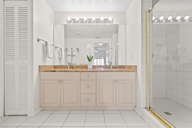 full bathroom featuring a closet, tile patterned flooring, a sink, and a shower stall