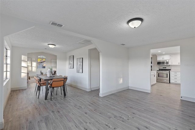 dining space with a textured ceiling and light hardwood / wood-style floors