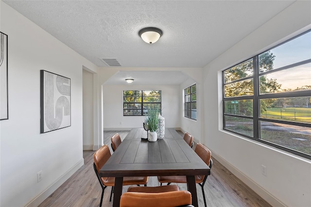 dining area with light hardwood / wood-style floors and a textured ceiling