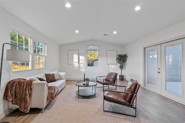 living room featuring french doors, vaulted ceiling, and light wood-type flooring