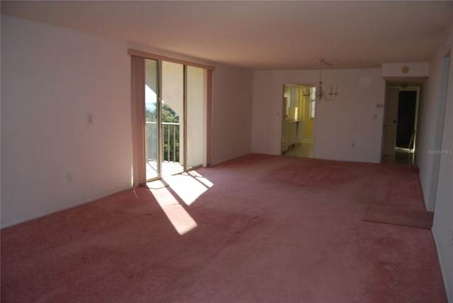 empty room with carpet floors and a notable chandelier