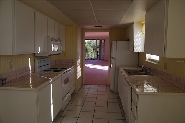 kitchen with tile countertops, white appliances, white cabinets, sink, and light tile patterned floors