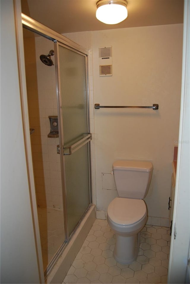 bathroom with tile patterned floors, vanity, toilet, and a shower with shower door