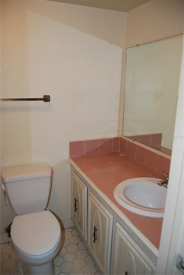 bathroom with toilet, vanity, and tile patterned floors