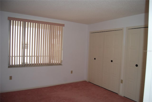 unfurnished bedroom with carpet, a textured ceiling, and multiple windows