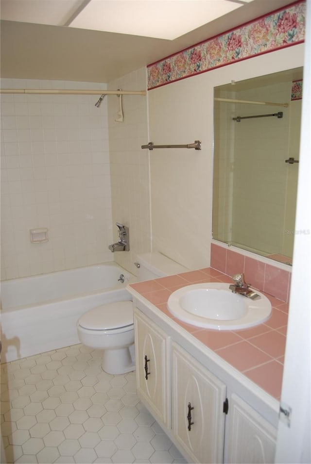 full bathroom with decorative backsplash, tile patterned floors, vanity, tiled shower / bath combo, and toilet