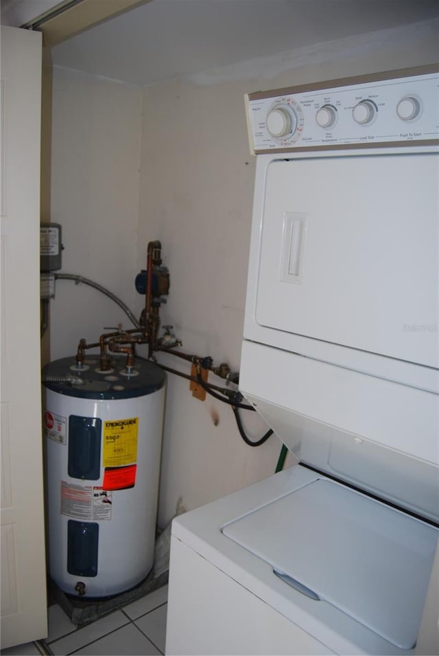 clothes washing area featuring stacked washer and clothes dryer, light tile patterned flooring, and water heater