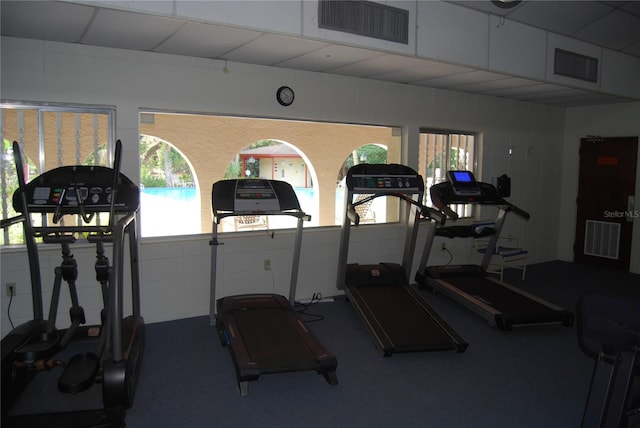 workout area with a paneled ceiling and a wealth of natural light