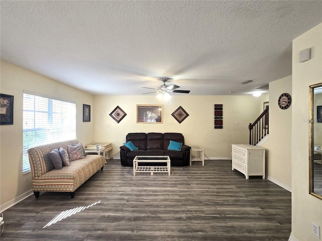 living room with a textured ceiling, ceiling fan, and dark wood-type flooring