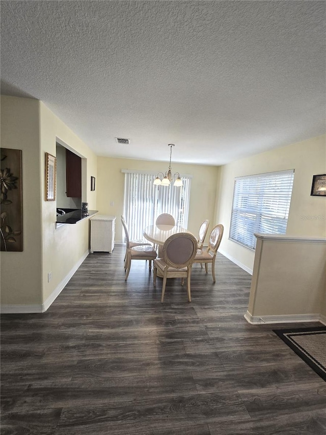 dining space featuring dark hardwood / wood-style flooring, a textured ceiling, and a notable chandelier