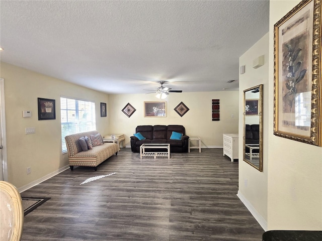 living room with a textured ceiling, ceiling fan, and dark wood-type flooring