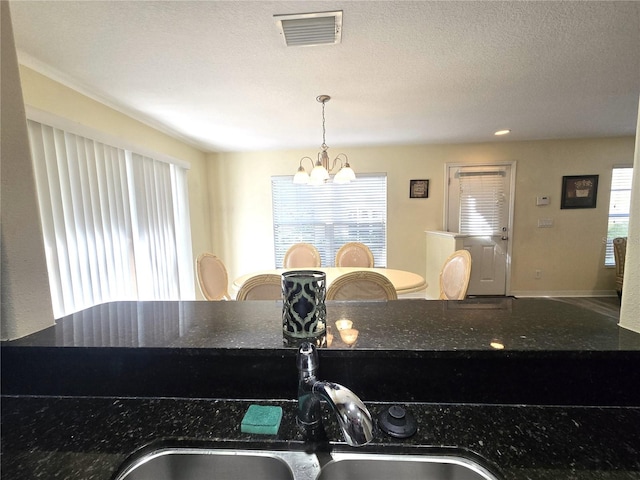 kitchen featuring dark stone counters, sink, a chandelier, and decorative light fixtures