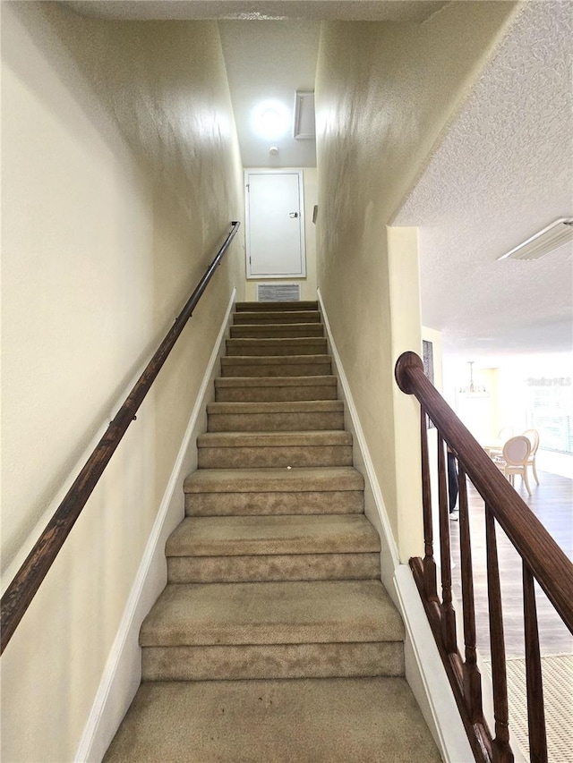 stairs featuring hardwood / wood-style floors and a textured ceiling