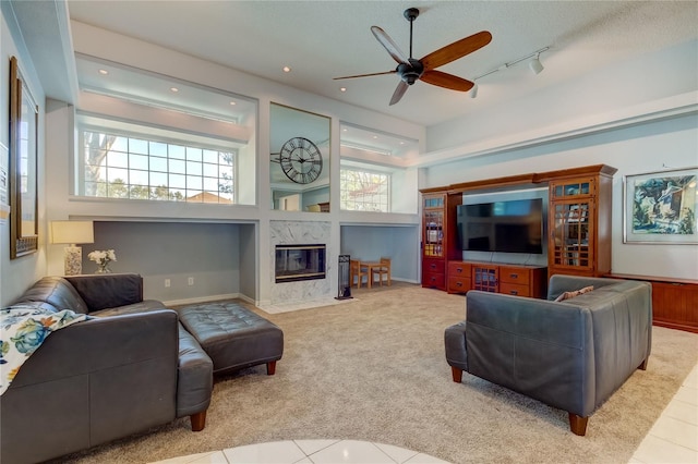 living room with light tile patterned floors, ceiling fan, plenty of natural light, and a premium fireplace