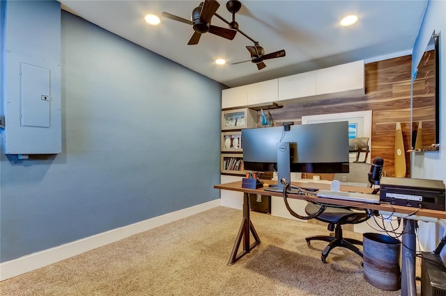 carpeted office space with wooden walls, ceiling fan, and electric panel