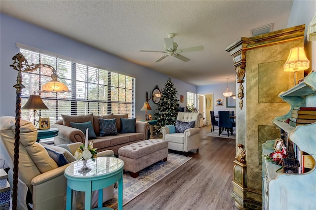 living room with ceiling fan, wood-type flooring, and a textured ceiling