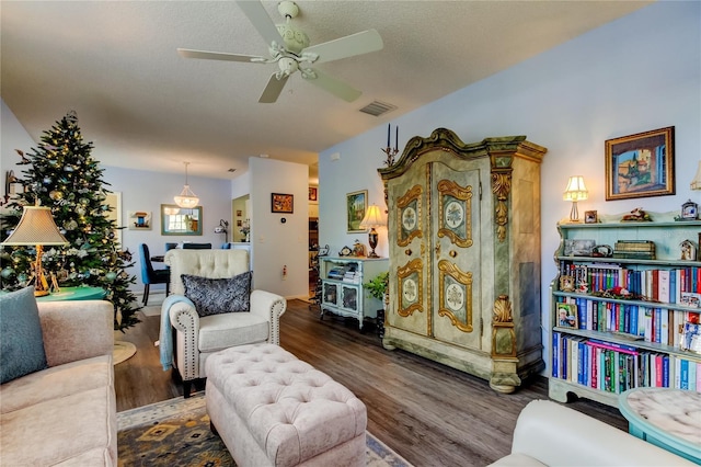 living room with ceiling fan, dark wood-type flooring, and a textured ceiling