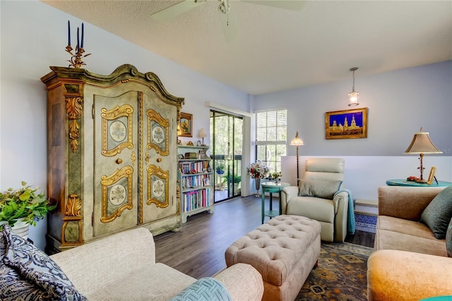 living room featuring a textured ceiling, ceiling fan, and dark wood-type flooring