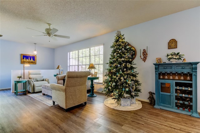 living room featuring hardwood / wood-style floors, ceiling fan, and a textured ceiling