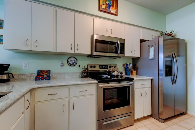 kitchen with white cabinetry, light tile patterned floors, light stone countertops, and appliances with stainless steel finishes