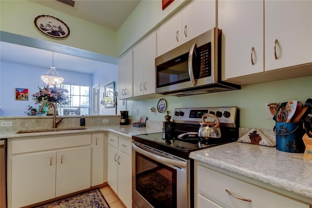 kitchen with appliances with stainless steel finishes, sink, decorative light fixtures, an inviting chandelier, and white cabinets