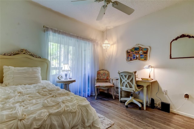 bedroom with hardwood / wood-style floors, ceiling fan, and a textured ceiling