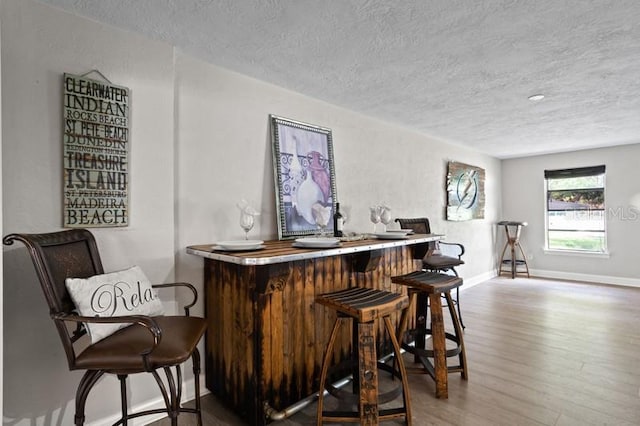 bar with hardwood / wood-style floors and a textured ceiling