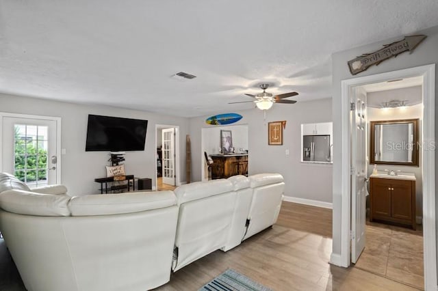 living room with ceiling fan, light hardwood / wood-style flooring, and sink