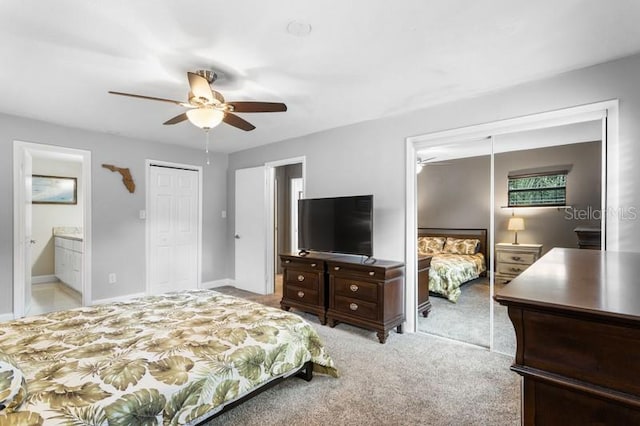 carpeted bedroom featuring ensuite bath, ceiling fan, and a closet