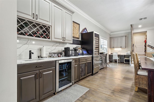 kitchen featuring crown molding, sink, beverage cooler, and light wood-type flooring