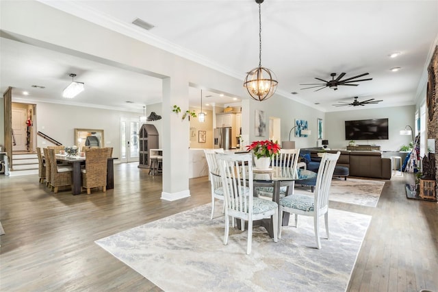 dining area featuring hardwood / wood-style flooring, ceiling fan with notable chandelier, and crown molding