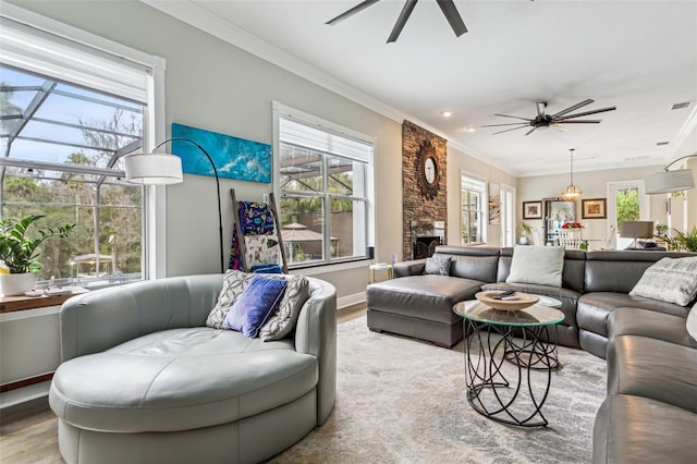 living room with ceiling fan, wood-type flooring, a fireplace, and ornamental molding