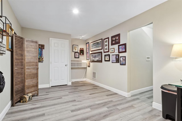 corridor featuring light hardwood / wood-style flooring and a wall unit AC